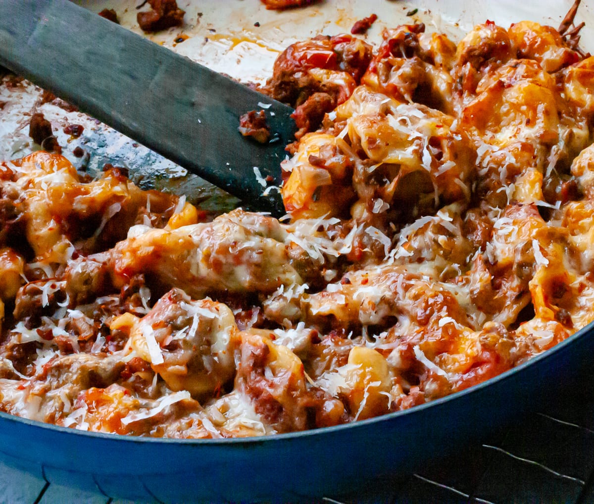 Pasta with cheese and ground beef in a braised pan with a spoon 