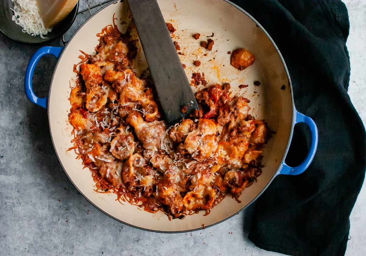 Pasta with cheese and ground beef in a braised pan with a spoon 