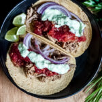 2 assembled citrus pulled pork tacos in a black bowl