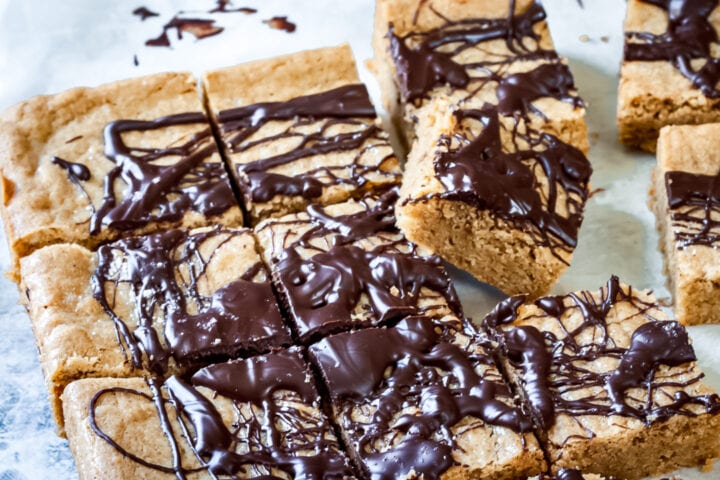 cut up blondies on parchment paper with one blondie slanted upward