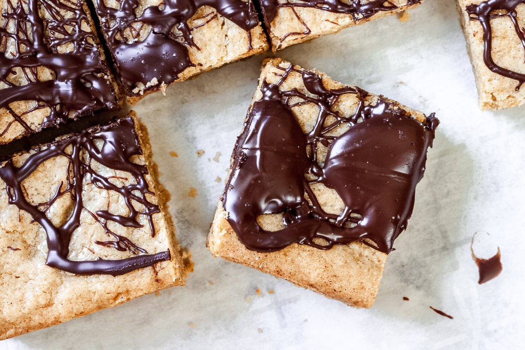 blondie covered in dark chocolate on parchment paper
