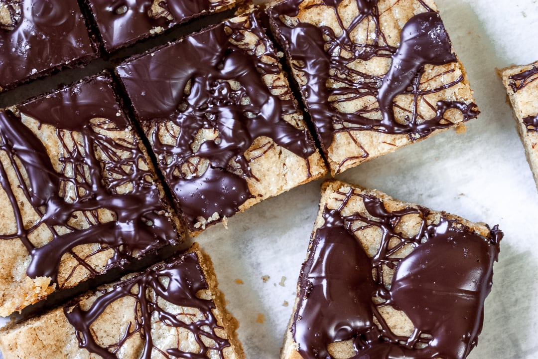 cut up salted caramel blondies on parchment paper with one blondie diagonal