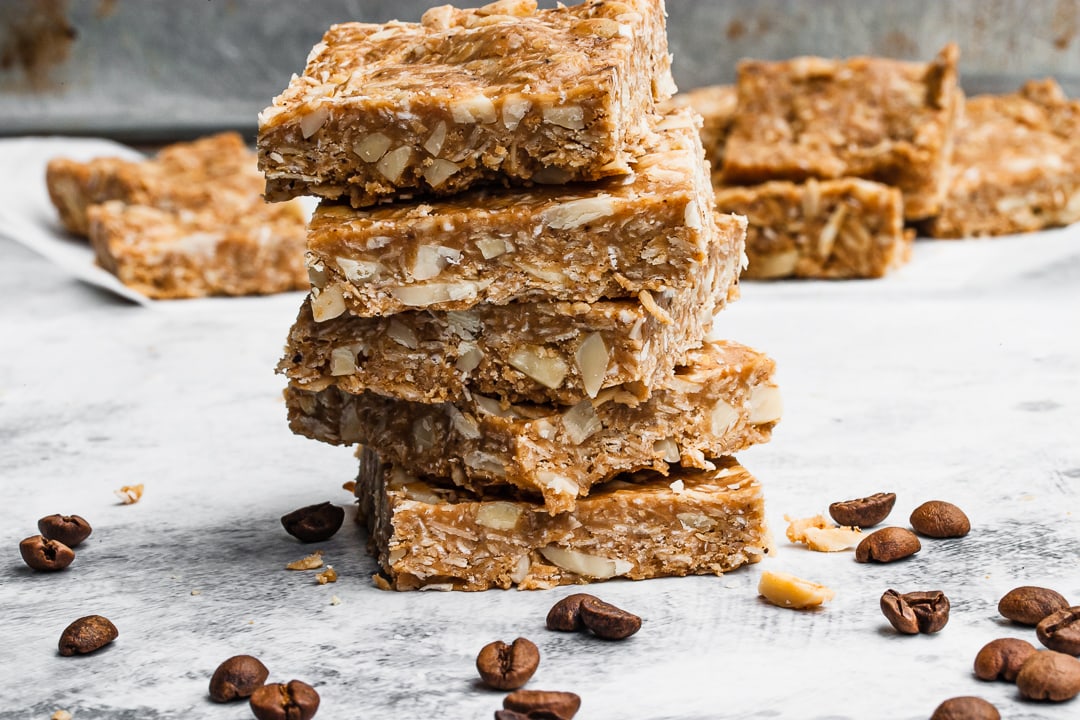 4 granola bars stacked on top of each other surrounded by coffee beans