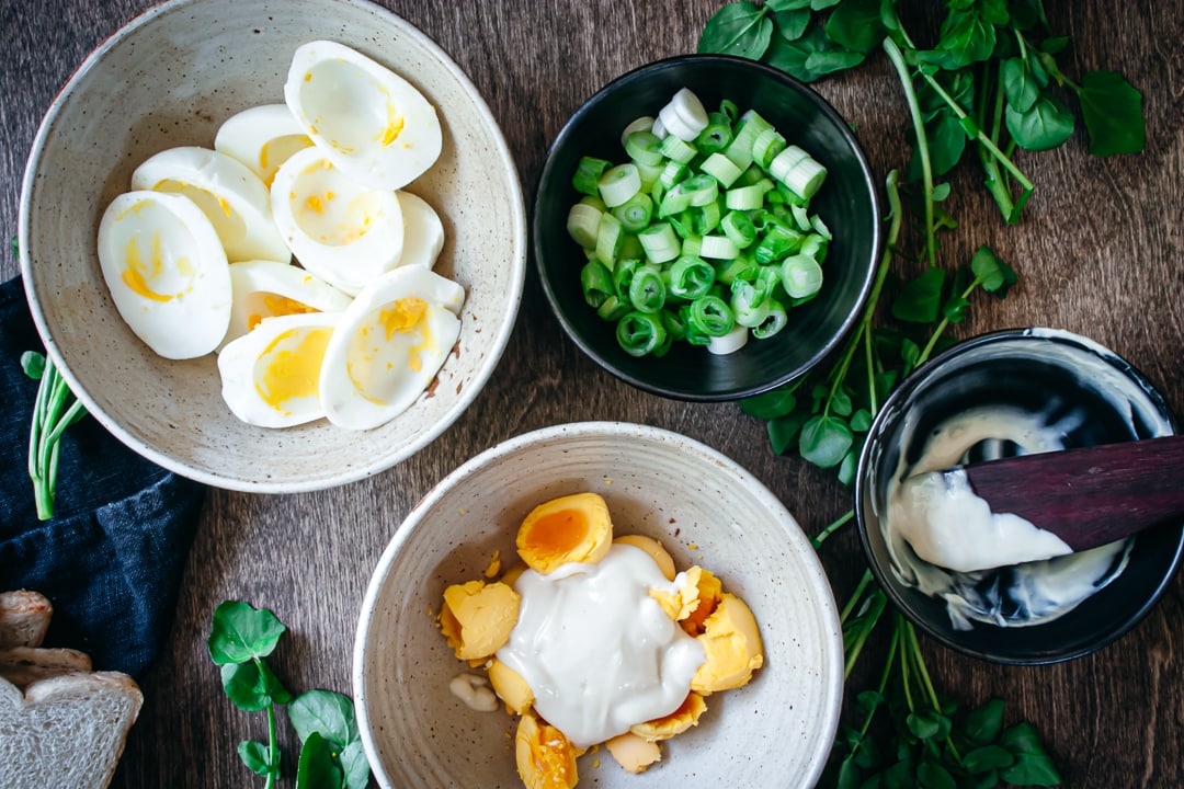 eggs and mayonnaise mixture in a bowl with egg whites and green onions on the side