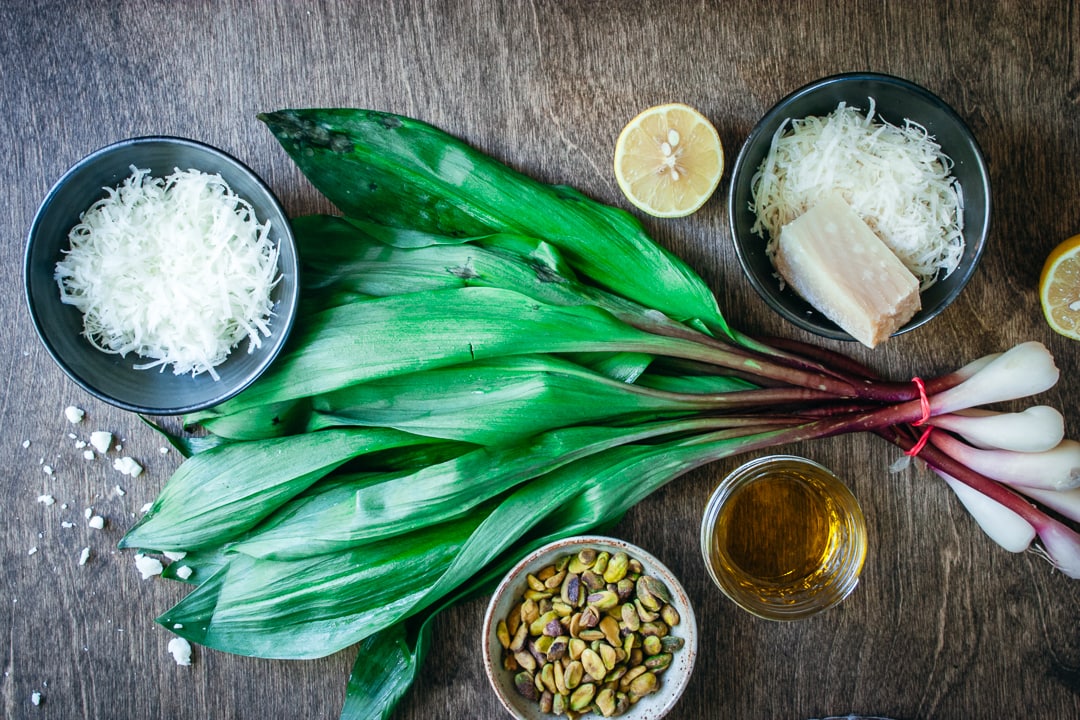 ramps surrounded by ingredients for the pesto on a wood background