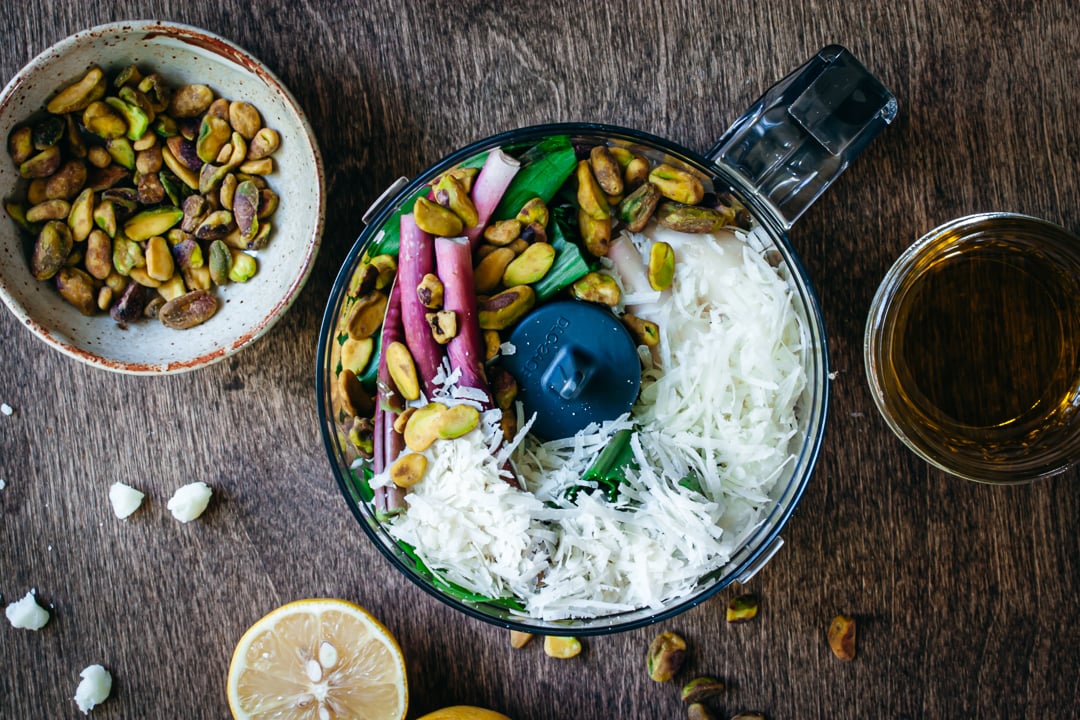 ramps, cheeses, and pistachios placed in a food processor bowl 