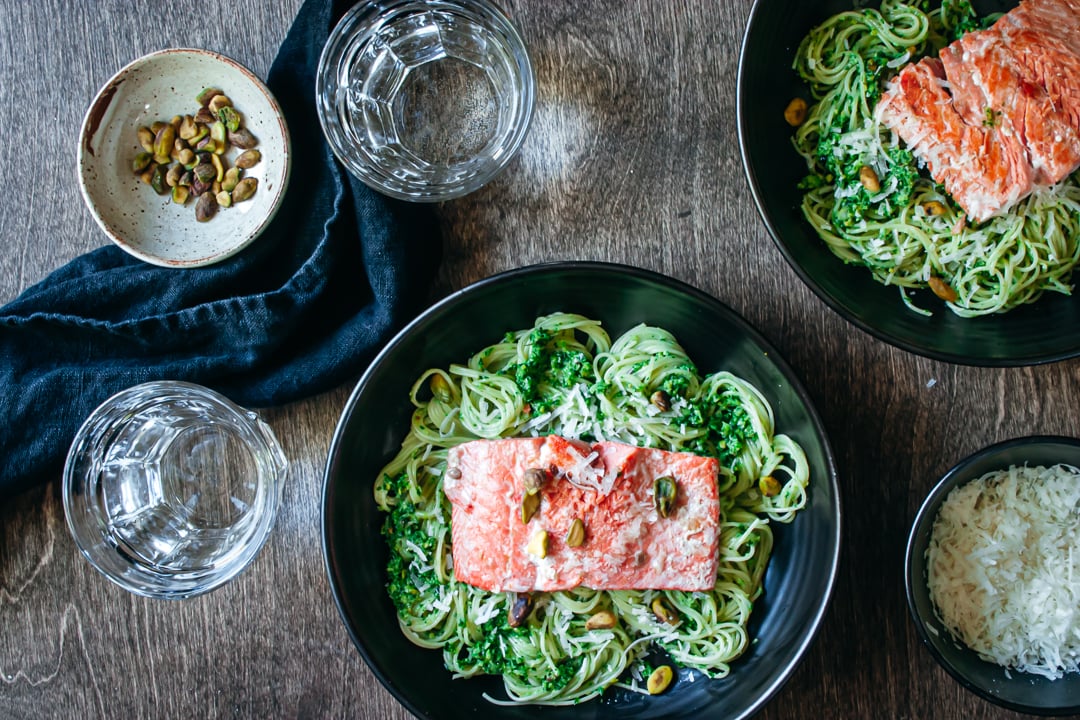 Sautéed Salmon on a bed of ramp pesto pasta with cheese, pistachios, and glasses of water on the side