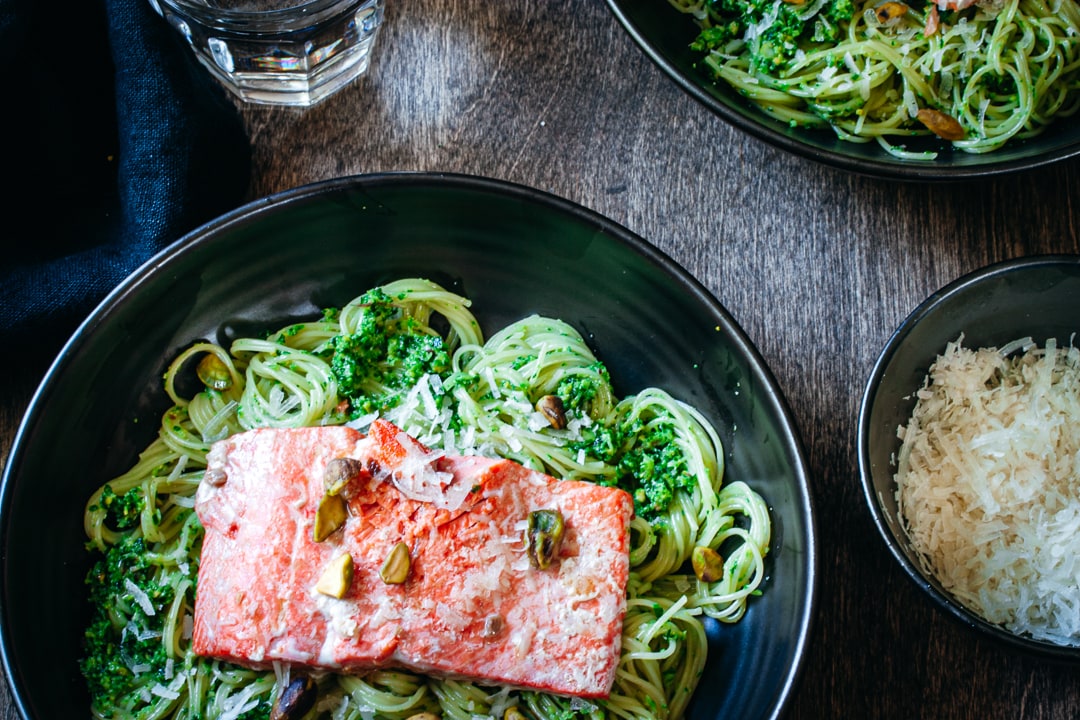 Sautéed Salmon on a bed of ramp pesto pasta with cheese, pistachios, and glasses of water on the side