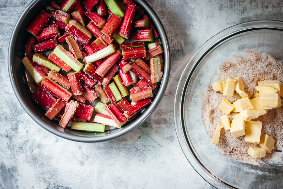 rhubarb covered with sugar in a bowl and crumble mixture with butter in a second bowl
