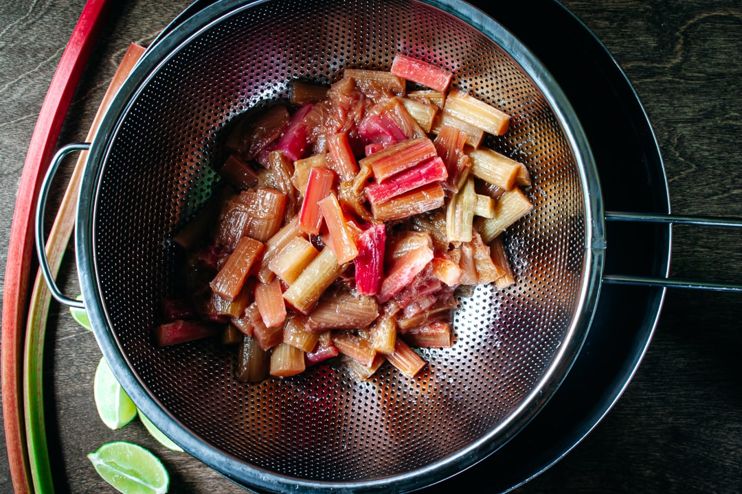 rhubarb in a strainer that is sitting on top of a bowl