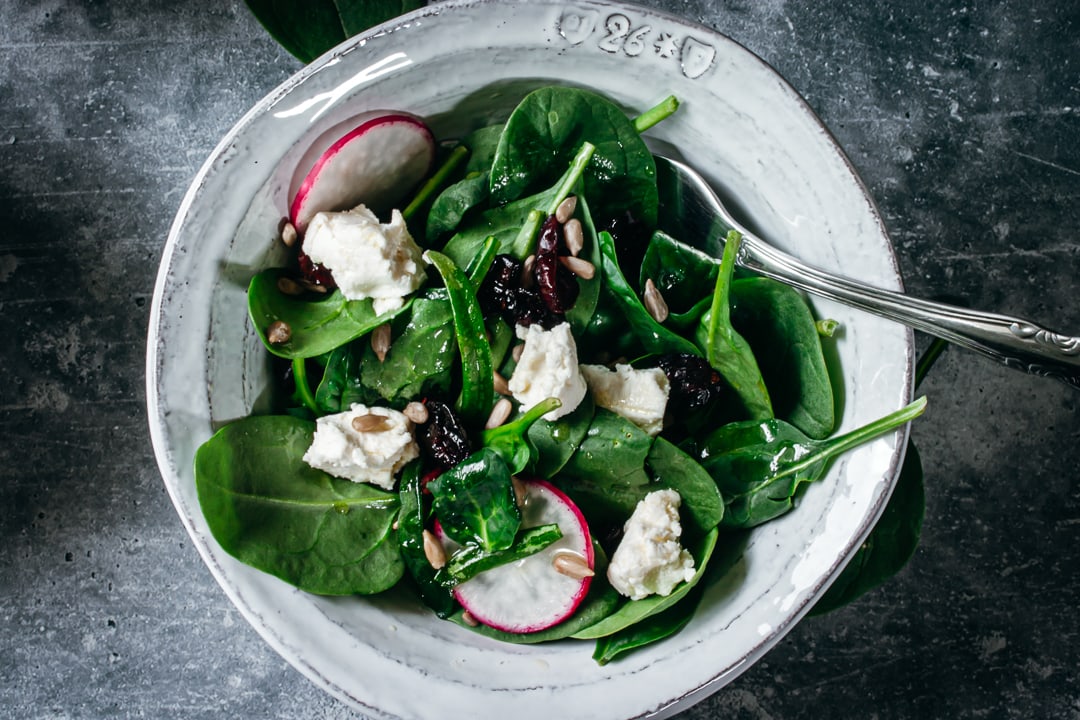 Simple Spinach Salad in a white bowl with a fork