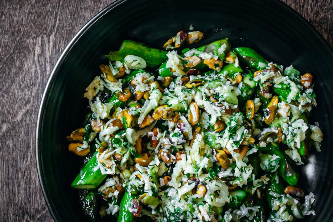 stove top asparagus with pistachios and herbs in a black serving bowl