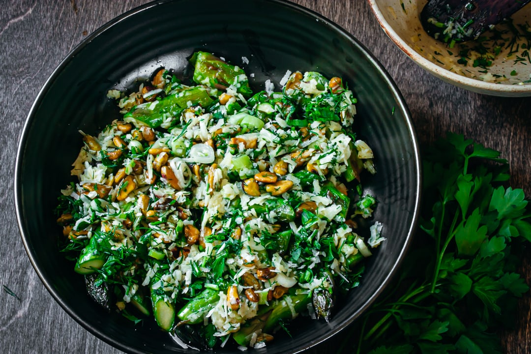 Finished Stove Top Asparagus with pistachios and herbs in a black serving bowl