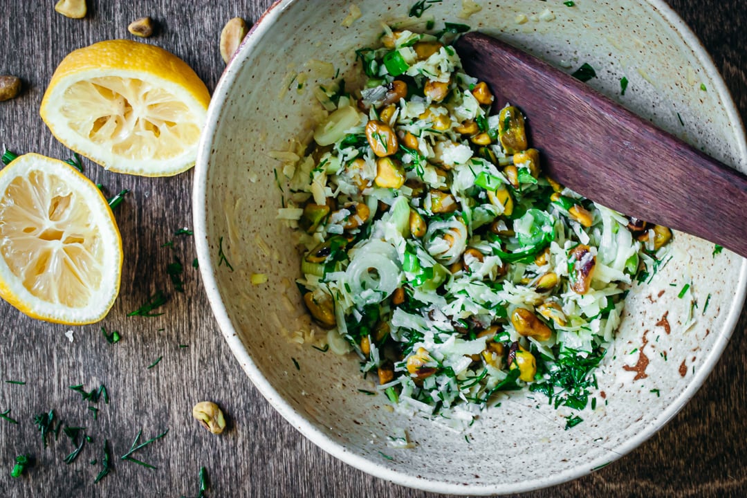 pistachios, cheeses, and herbs mixed with olive oil and green onions in a bowl