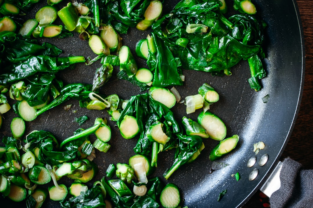 sautéed asparagus, spinach, and spring onions in a skillet