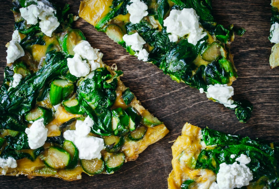 Cooked Veggie Frittata cut into triangles on a wood background