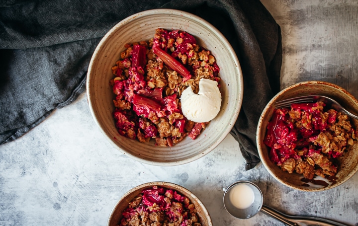 rhubarb crisp in 3 bowls with an ice cream scoop on the side
