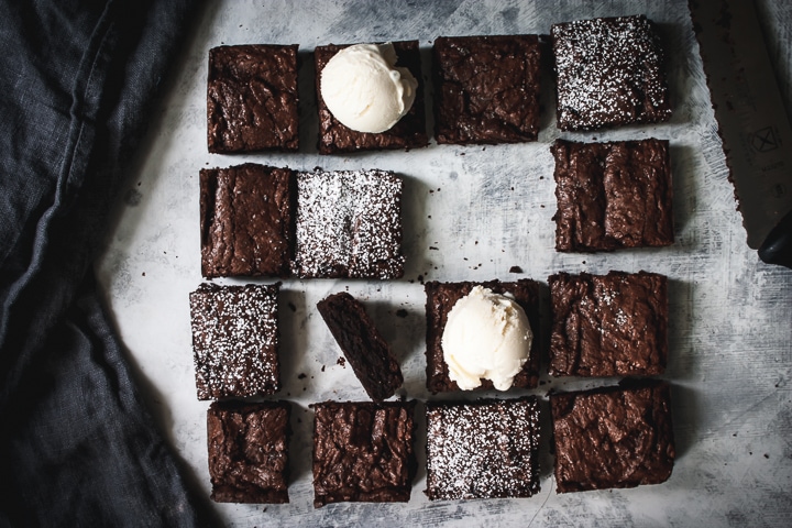 bittersweet salted rye brownies cut into squares and topped with powdered sugar and ice cream