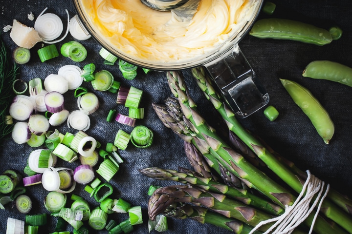 whipped butter in a food processor bowl, chopped scallions, and asparagus spears