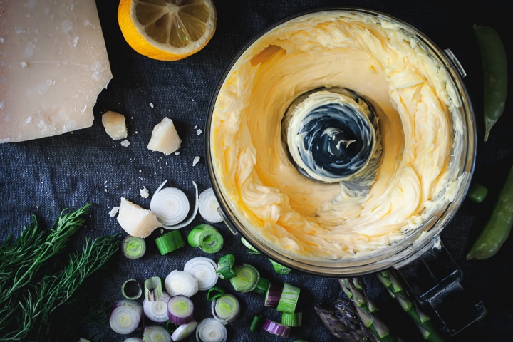 whipped butter in a food processor bowl, chopped scallions, and asparagus spears