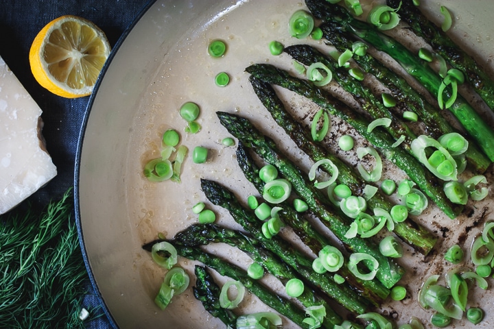 charred asparagus and raw peas in a braiser pan with lemon and parmesan cheese on the side