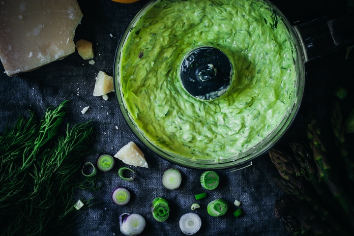 scallion compound butter in food processor bowl with chopped scallions and asparagus on the side