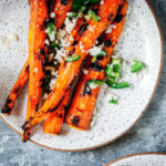 grilled carrots with jalapeño, lime, and cotija cheese on a white plate