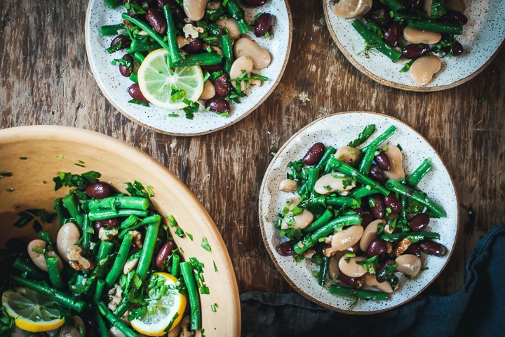 3 bean salad with lemon and dill on 3 white whites with the serving bowl on the side