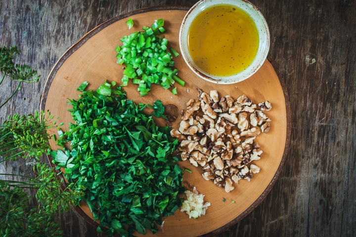 chopped ingredients for the dressing on a wood cutting board