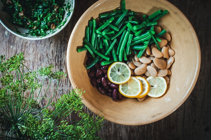 butter beans, kidney beans, green beans, and lemons in a serving bowl with dill and the lemon and dill dressing on the side