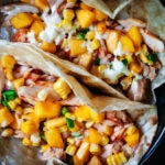 Baked fish tacos topped with peach and jalapeño salsa and Mexican crema