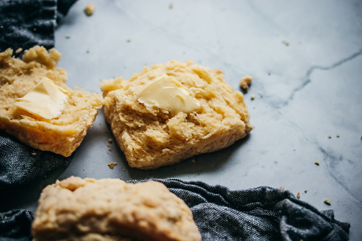 torn open small batch buttermilk biscuit with a pad of butter and a napkin on the side