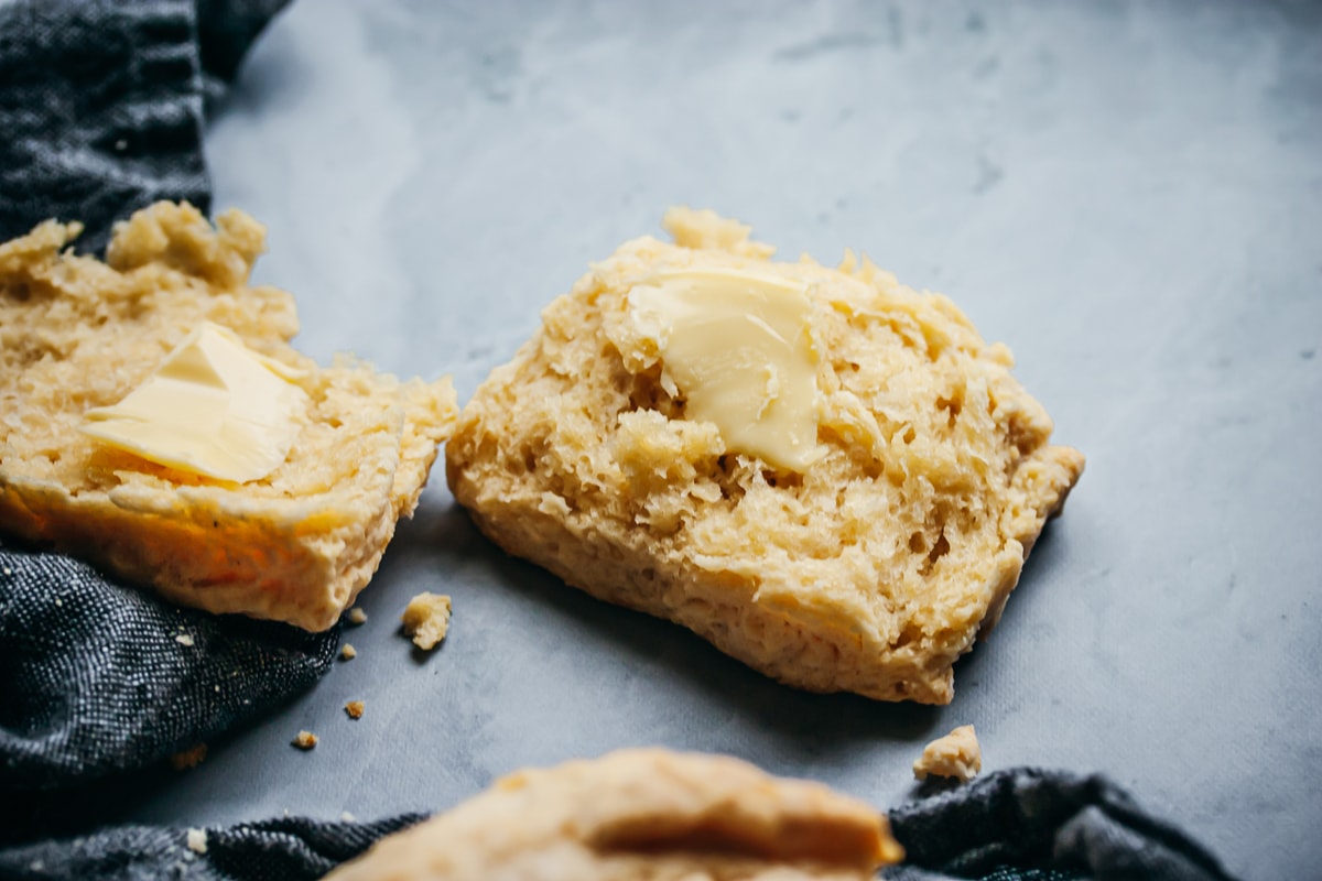 torn open small batch buttermilk biscuit with a pad of butter and a napkin on the side