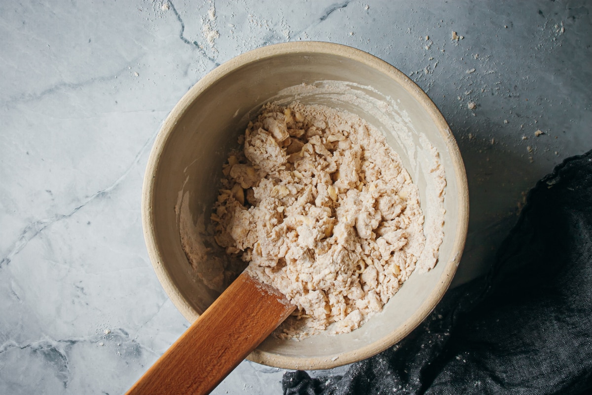 wet and dry ingredients mixed together in a bowl with a wooden spatula