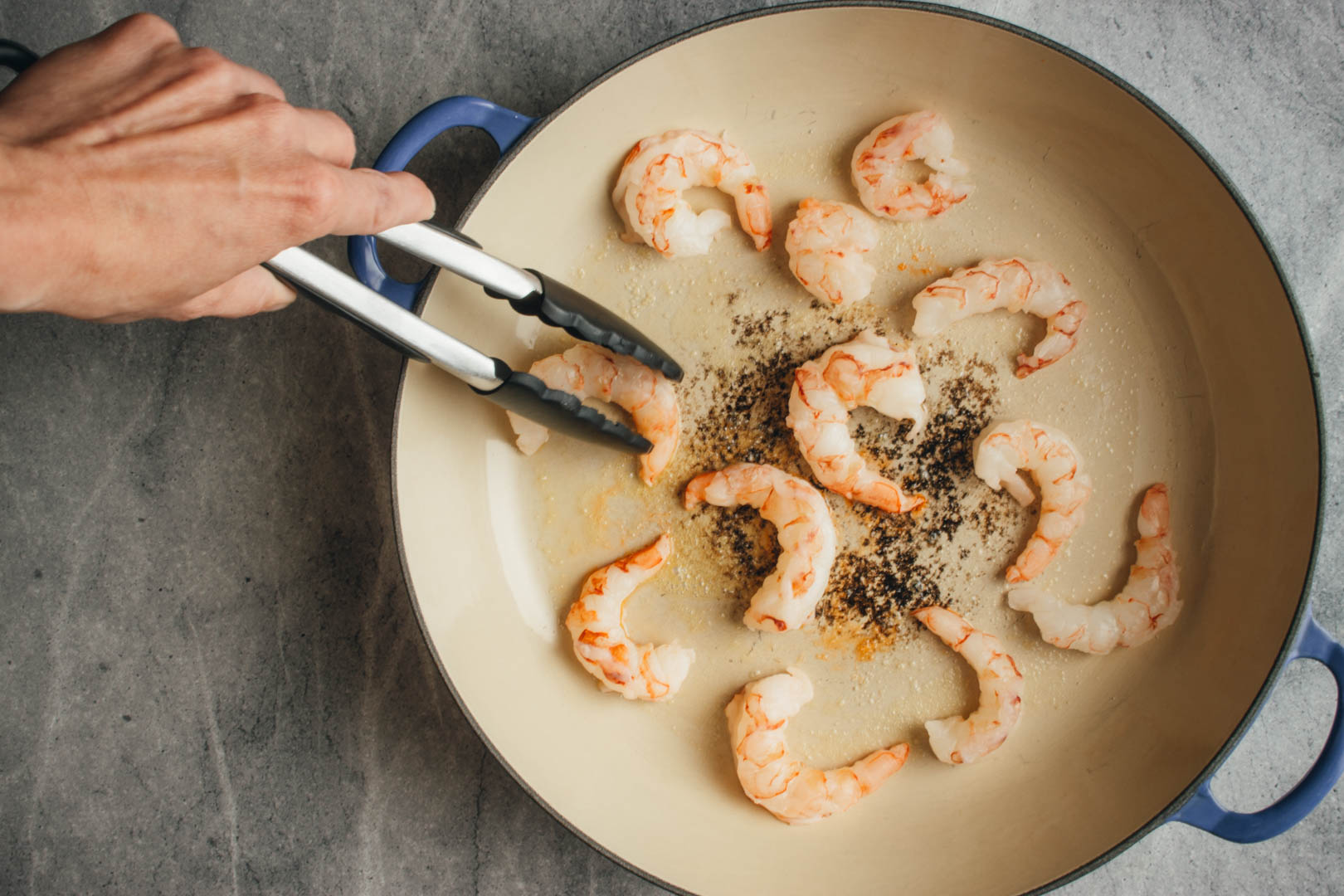 Saute shrimp in a skillet with tongs on the side