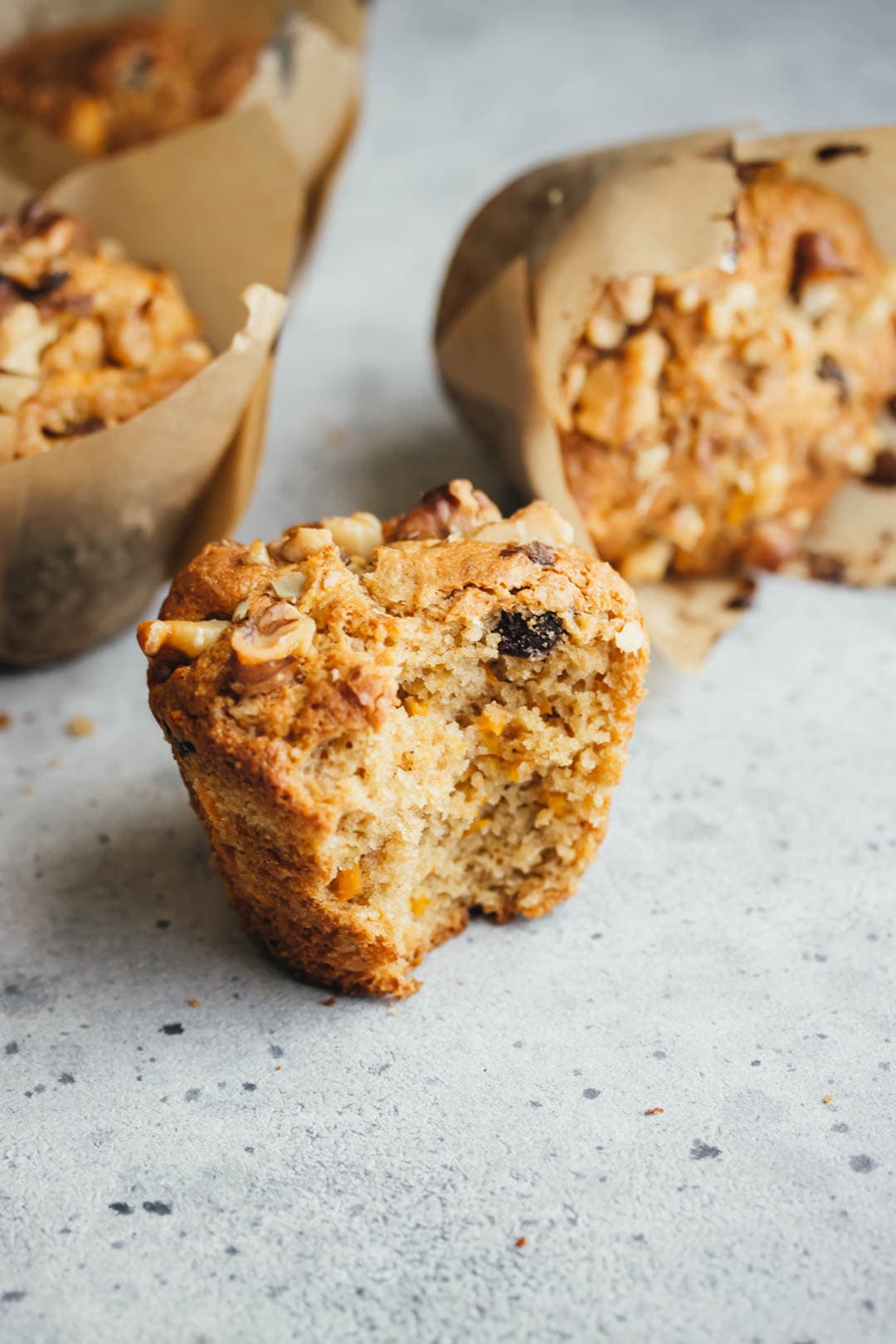 carrot muffin with a large bite out of it with muffins in the background