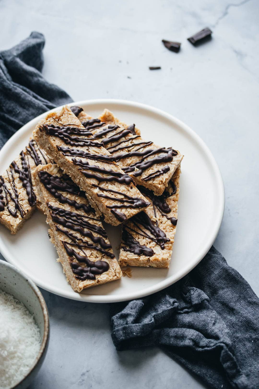 dark chocolate coconut granola bars stacked on a plate with a napkin on the side