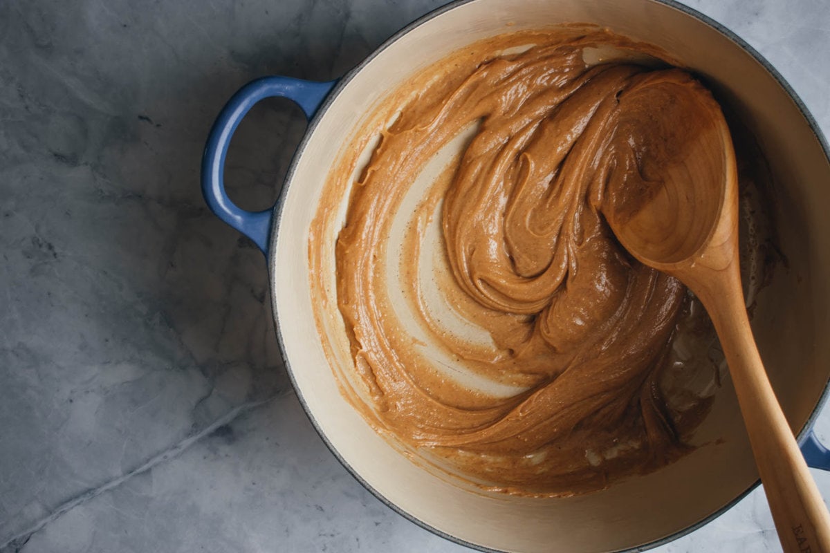 peanut butter and honey mixed together in a wide skillet with a wooden spoon on the side