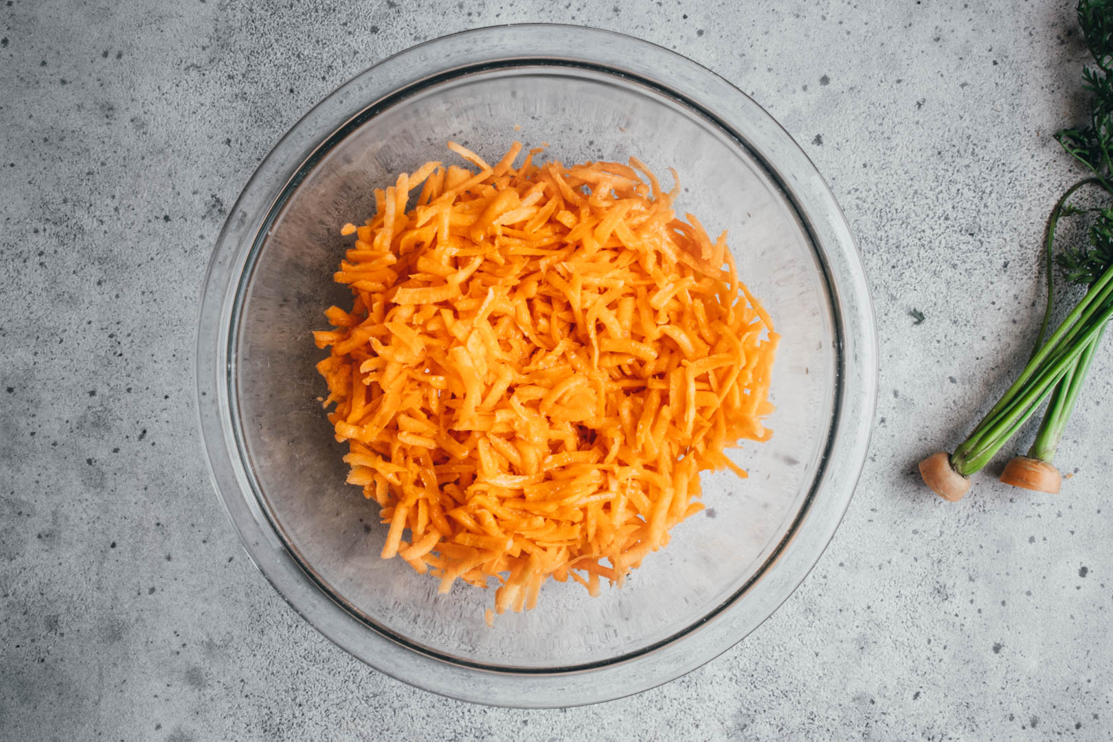 shredded carrots in a glass bowl with salt sprinkled on top