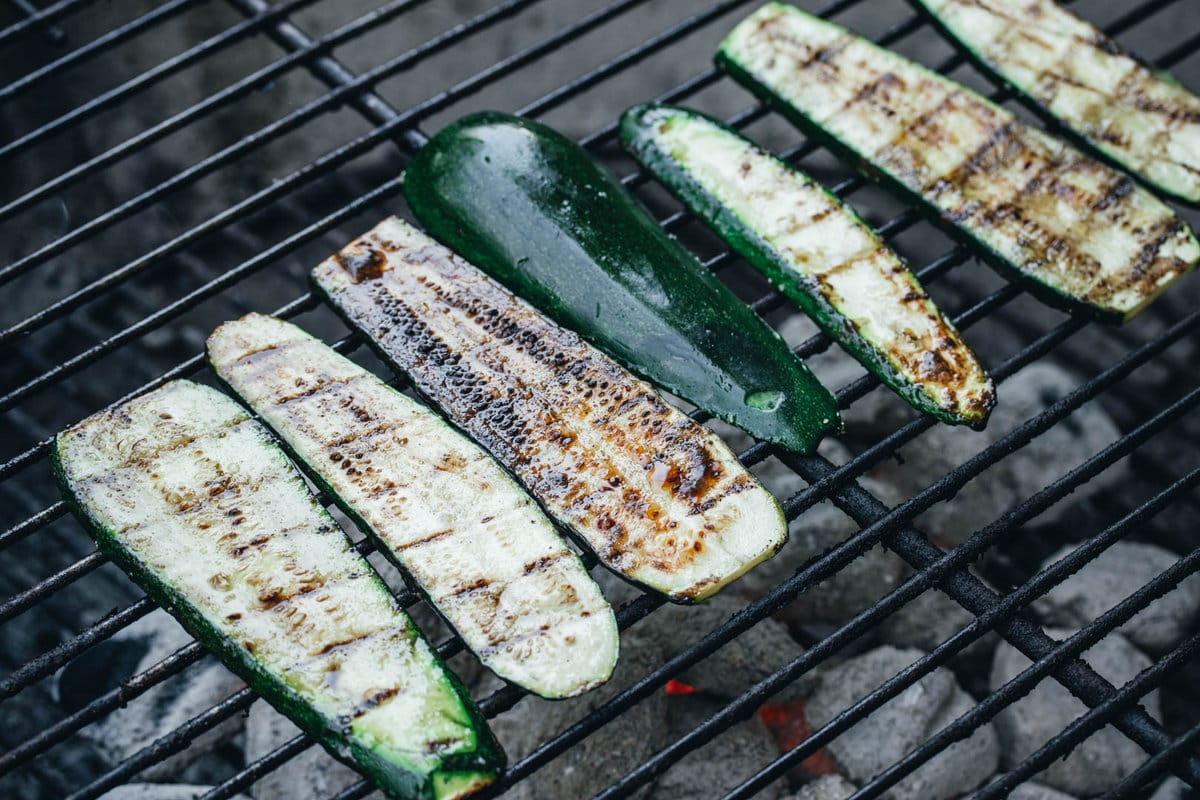 summer squash planks cooking on a charcoal grill