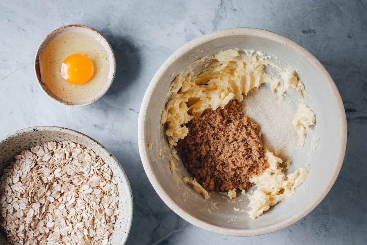 butter and sugar whipped together in a large bowl with oats and an egg on the side