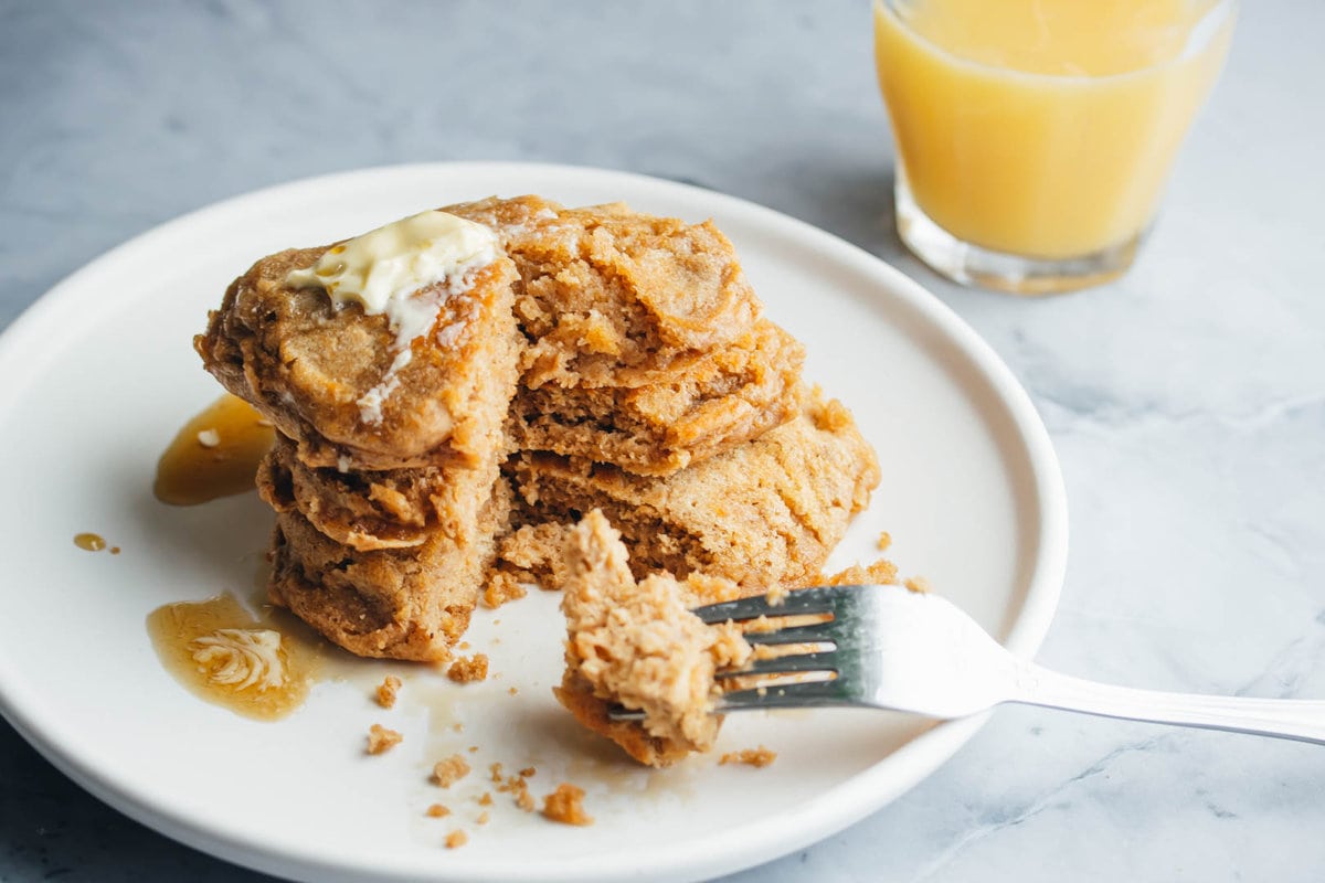 a stack of buttermilk pancakes for two topped with butter and maple syrup and a fork on the side