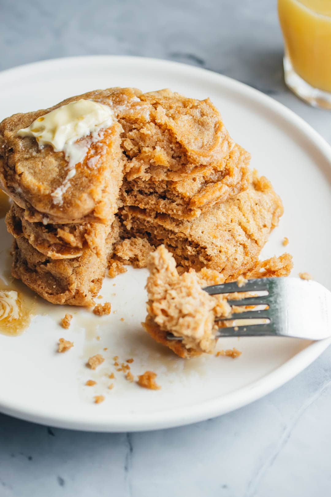 a stack of buttermilk pancakes for two topped with butter and maple syrup and a fork on the side