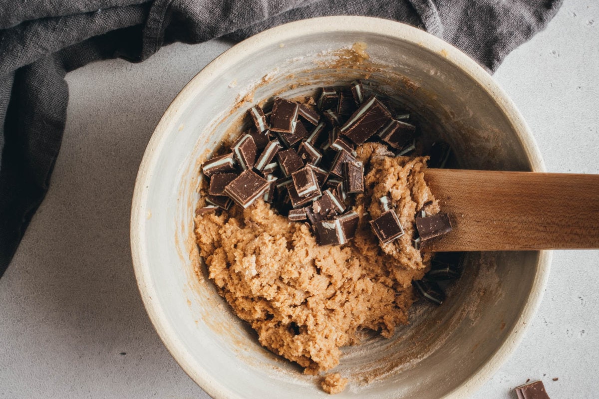 cookie dough with andes mints in a large bowl with a wooden spoon on the side