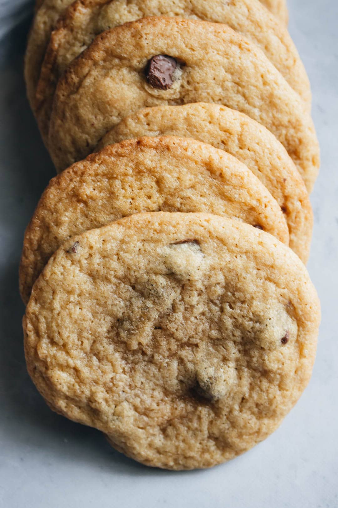 thin and chewy chocolate chip cookies stacked in a row