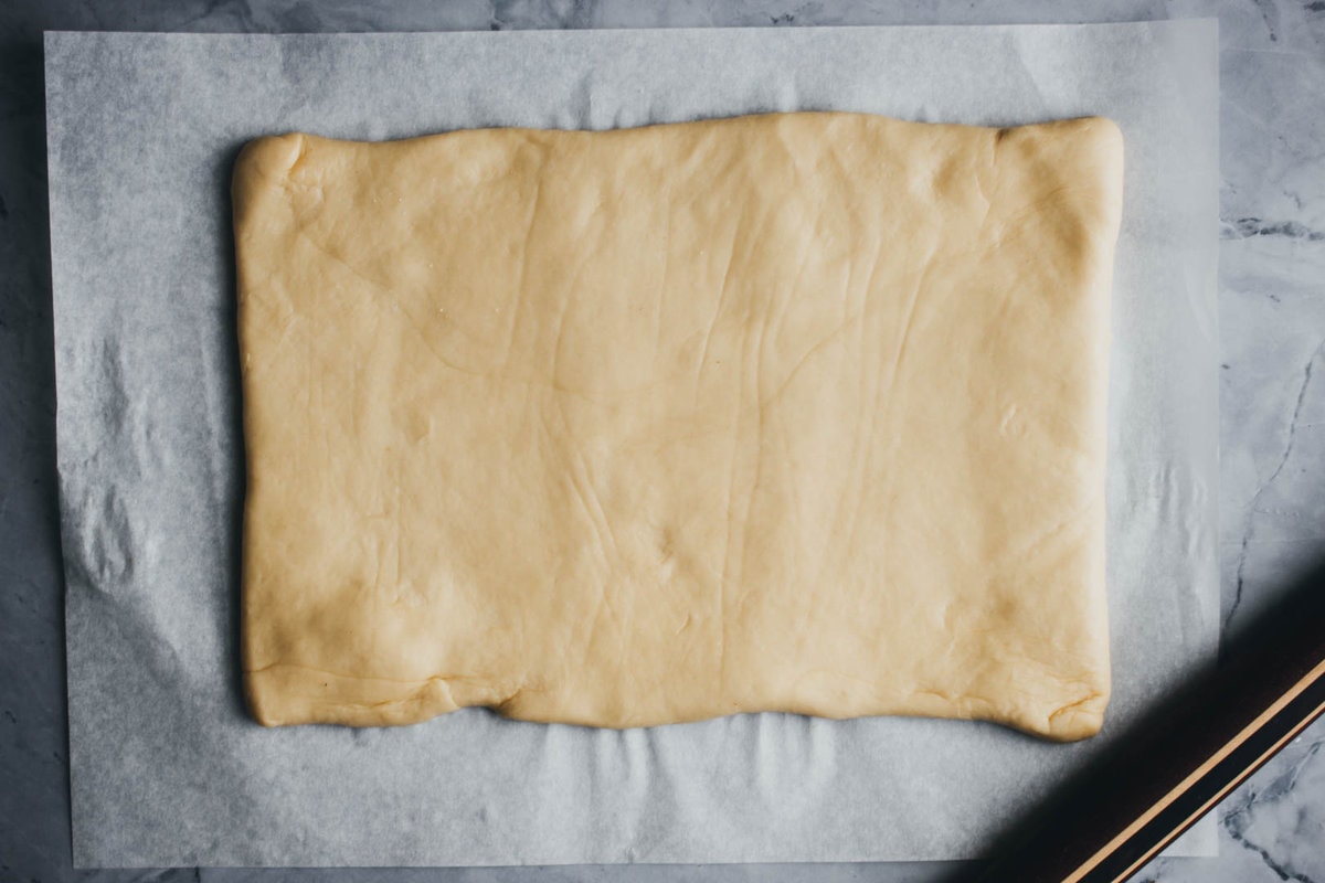 dough rolled out into a rectangle with a rolling pin on the side