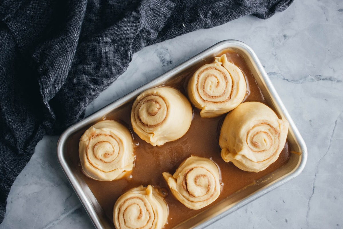 rolls doubled in size in a sheet pan with caramel on the bottom